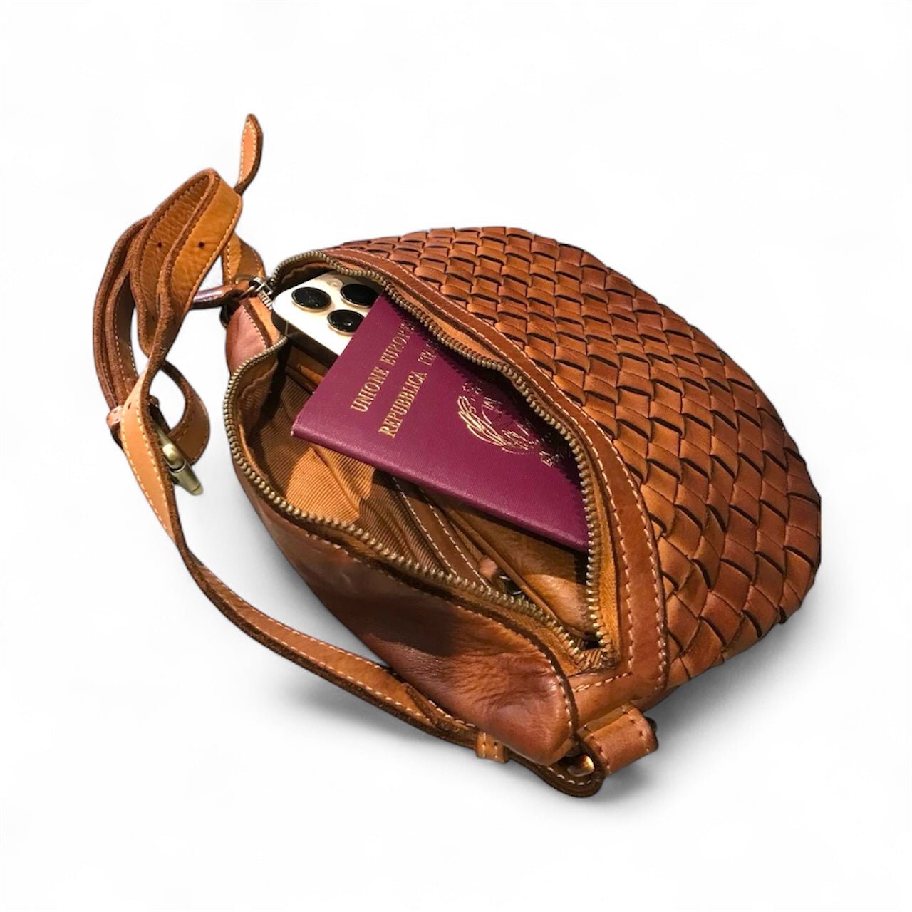 Tan woven handbag with a phone and passport inside on a white background