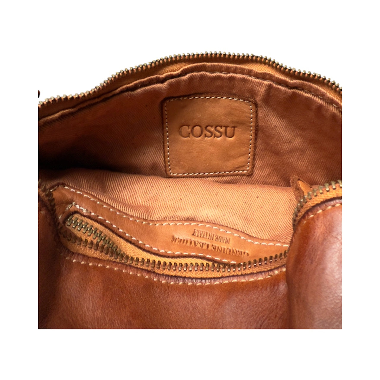 Close-up of a tan leather bag with 'COSSU' branding on a white background