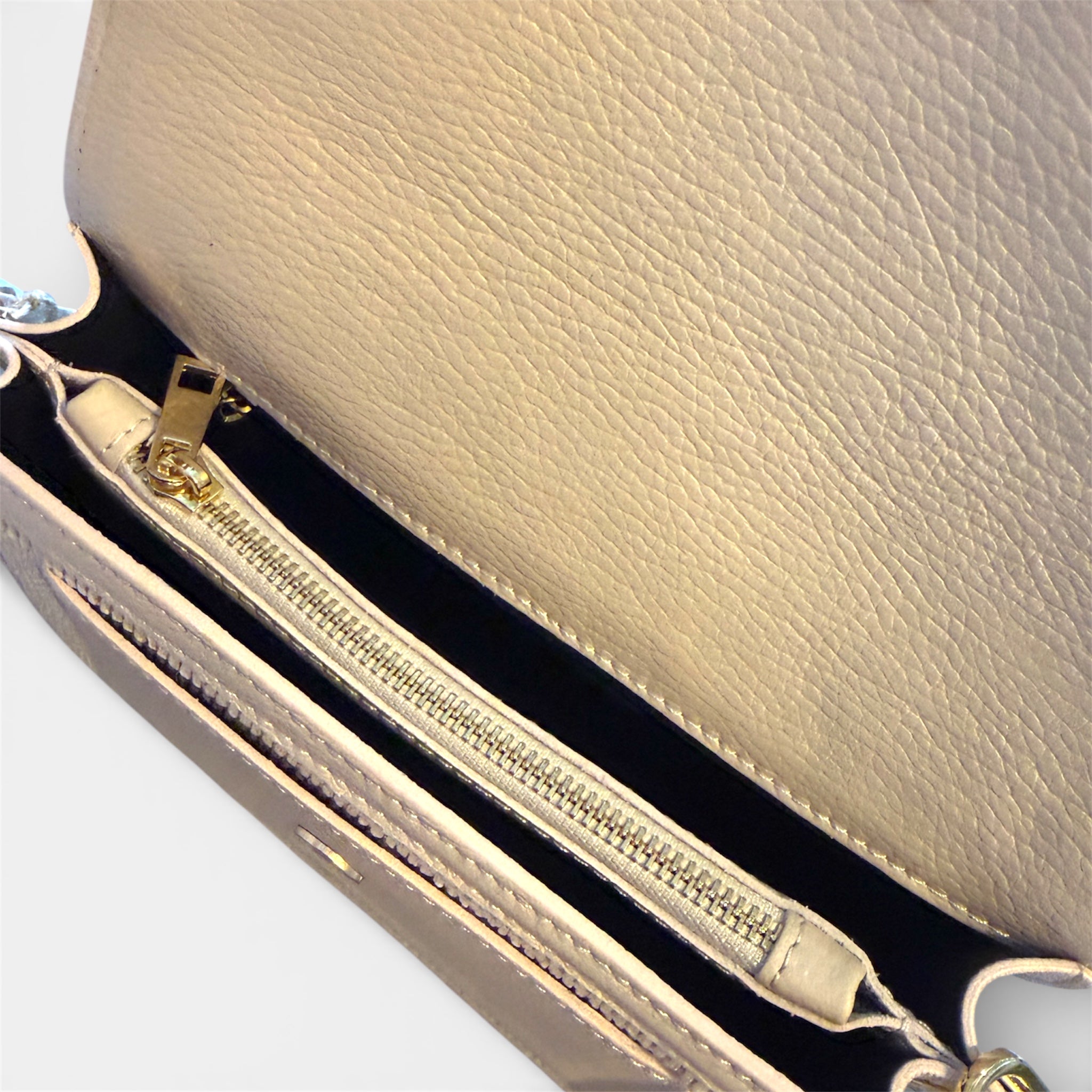 Close-up of a cream handbag with gold zipper 